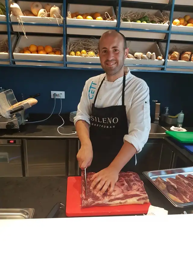 Fundador de Deseo Local cortando carne en la cocina de un restaurante
